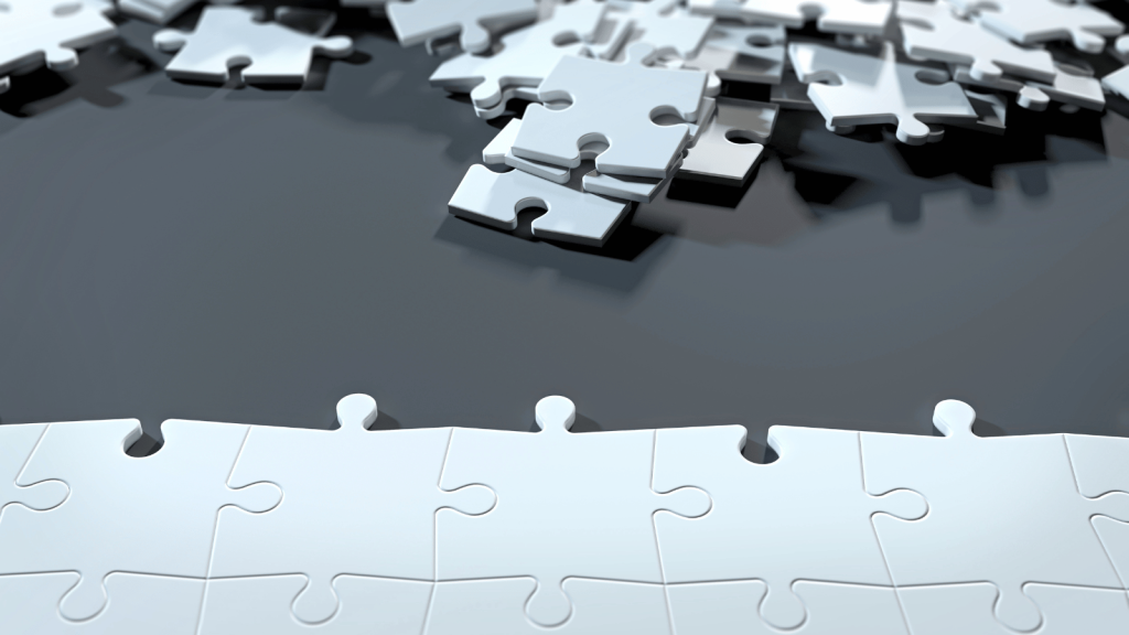 A nearly completed puzzle lies on a surface, with several loose pieces scattered above the assembled section.