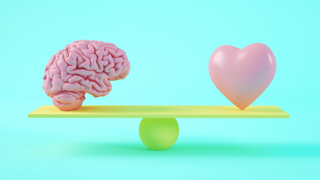 A stylized 3D illustration of a brain and a heart balanced on a seesaw-like plank over a round fulcrum against a bright aqua background.