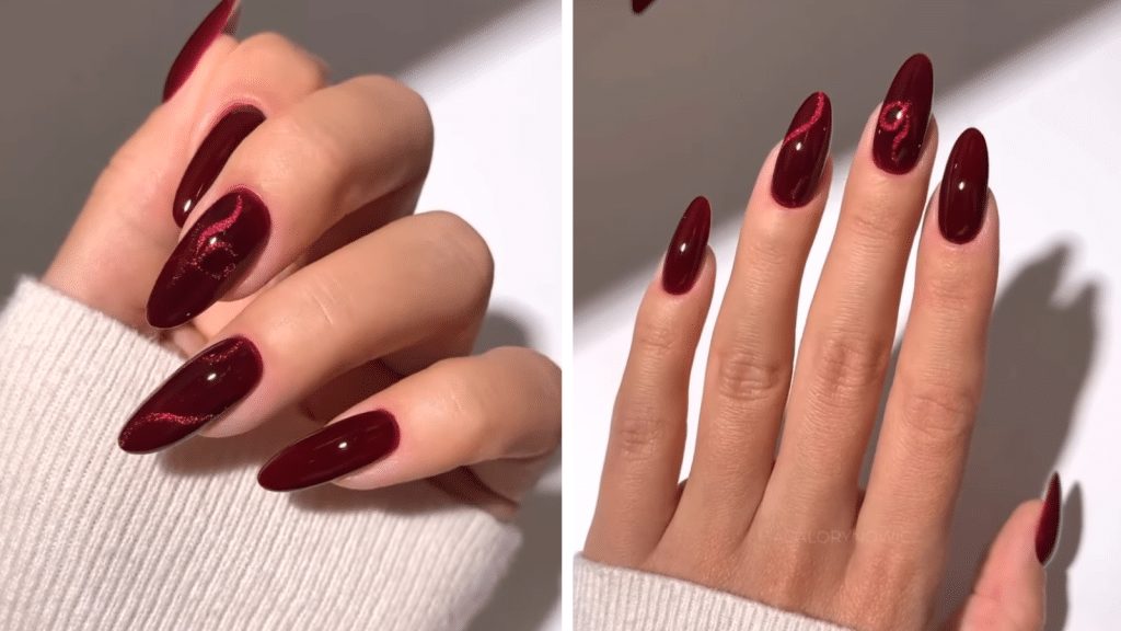Long burgundy cat-eye nails with deep red magnetic swirls. Elegant and jewel-toned, these Christmas nails convey the richness associated with old money Christmas nails.