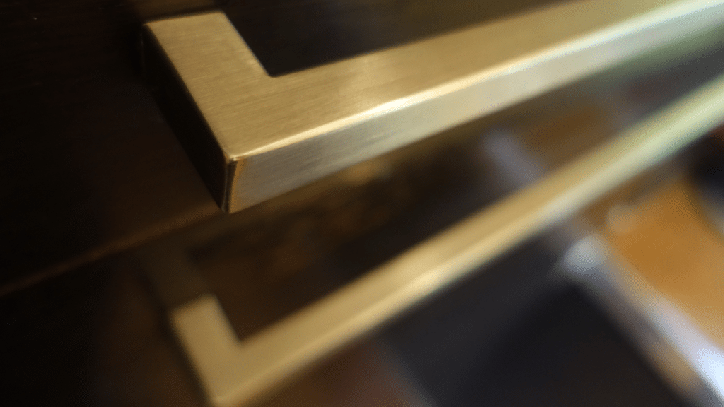 Close-up of brass drawer pulls on closet cabinetry, showing small walk-in closet ideas that elevate storage with simple hardware upgrades.
