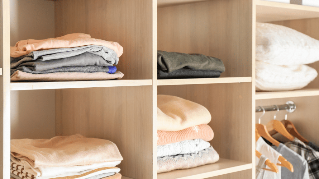 Open closet cubbies with folded clothes and storage bins, showcasing small walk-in closet ideas that maximize vertical space.