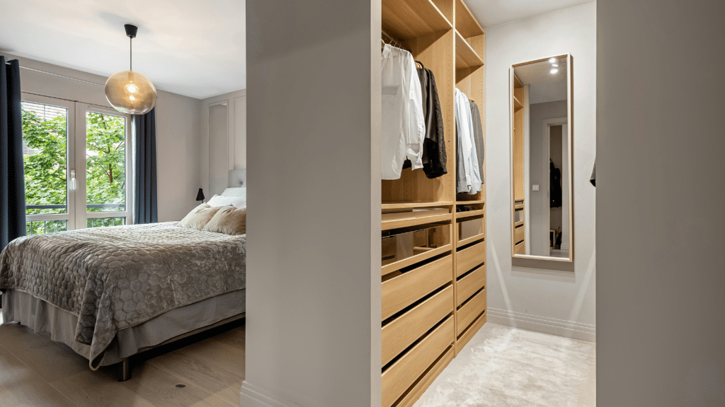Small walk-in closet built into a bedroom layout with open shelving and drawers, illustrating practical small walk-in closet ideas.