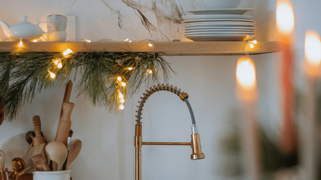 Warm kitchen counter decor with open shelving, stacked white dishes, wooden utensils, and soft accent lighting