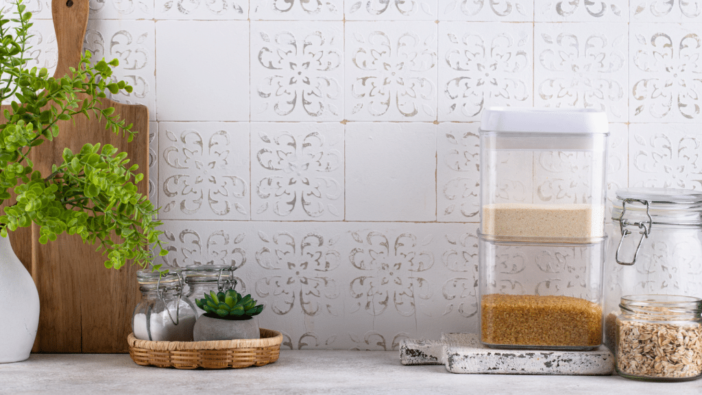 Kitchen counter styled with simple containment using clear food containers, glass jars, and a tray to keep everyday items organized and easy to maintain.
